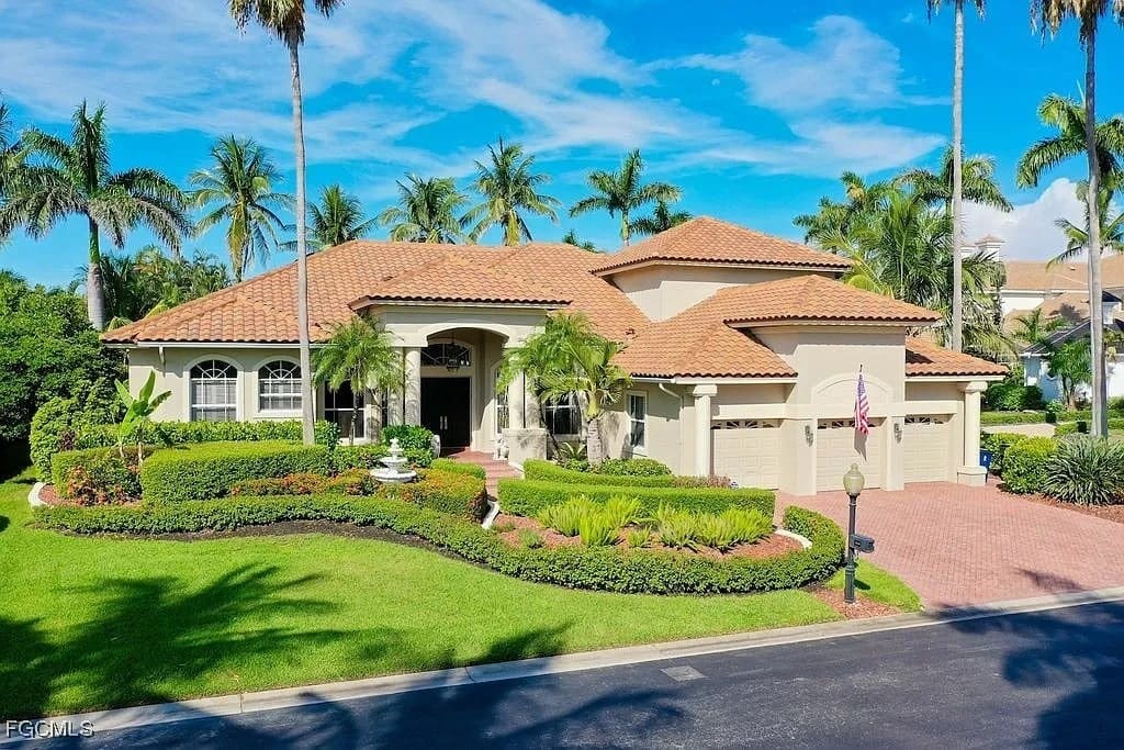 Large Mediterranean-style house with a red-tiled roof, surrounded by palm trees and manicured lawn.
