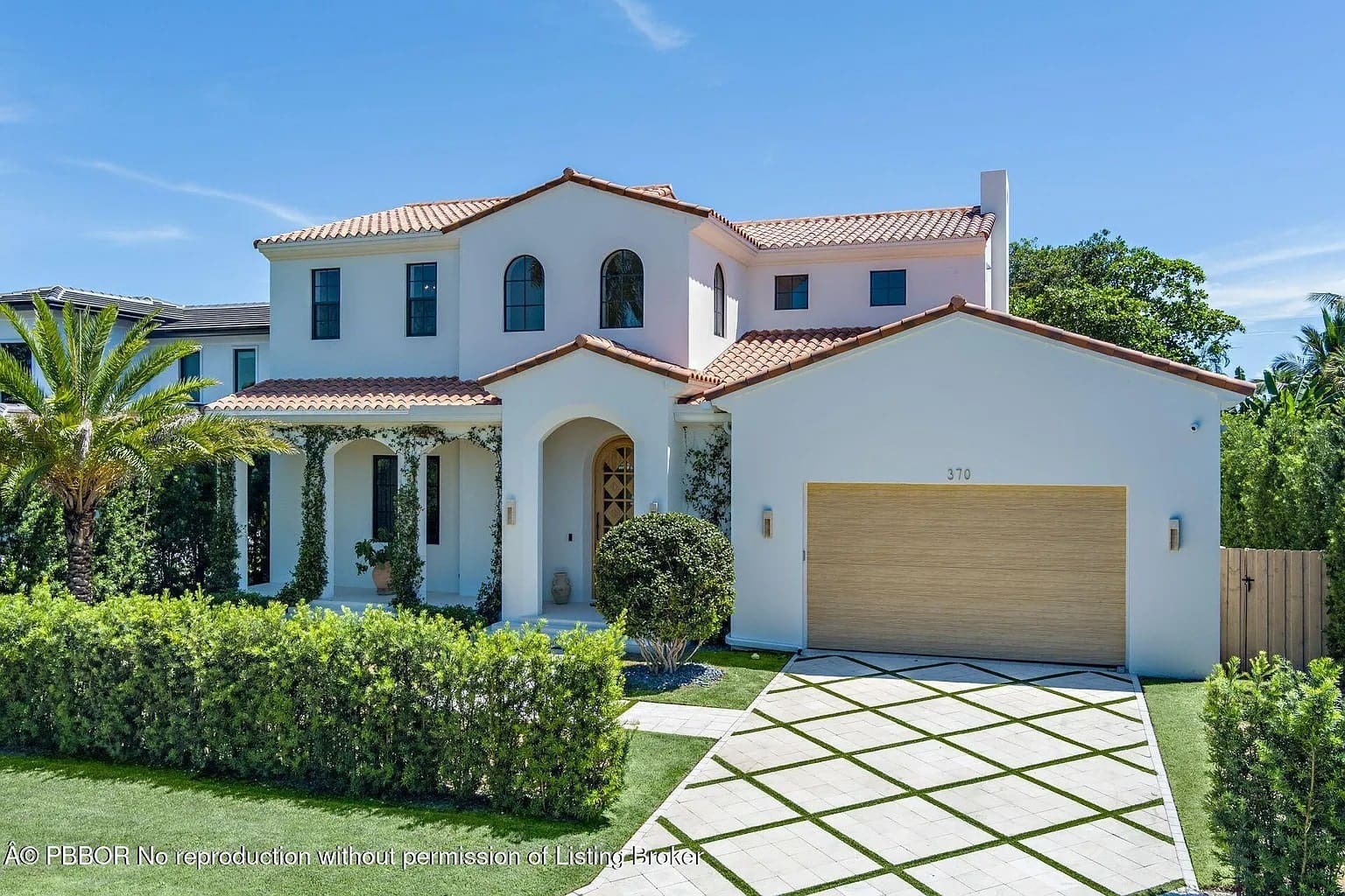 Two-story Mediterranean-style house with a red-tiled roof, garage, and manicured lawn.

