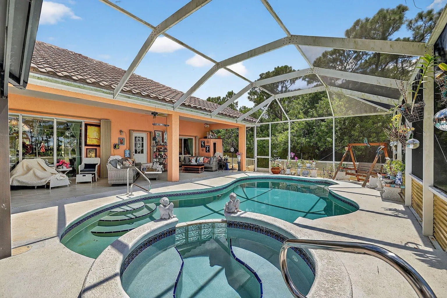 Outdoor pool area with a hot tub, patio seating, and screened enclosure.