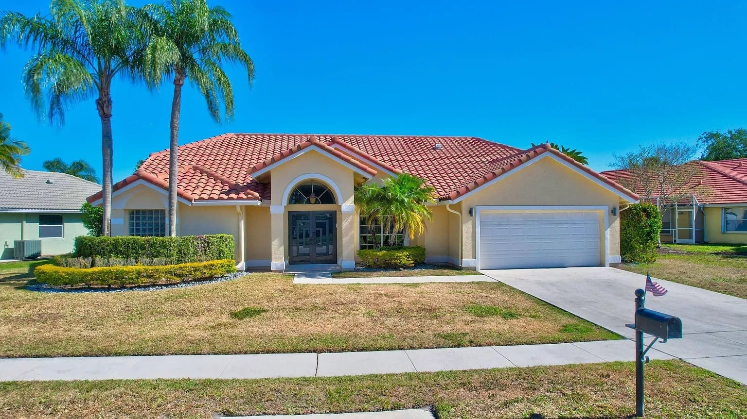 Single-story house with red-tiled roof, palm trees, and a two-car garage.