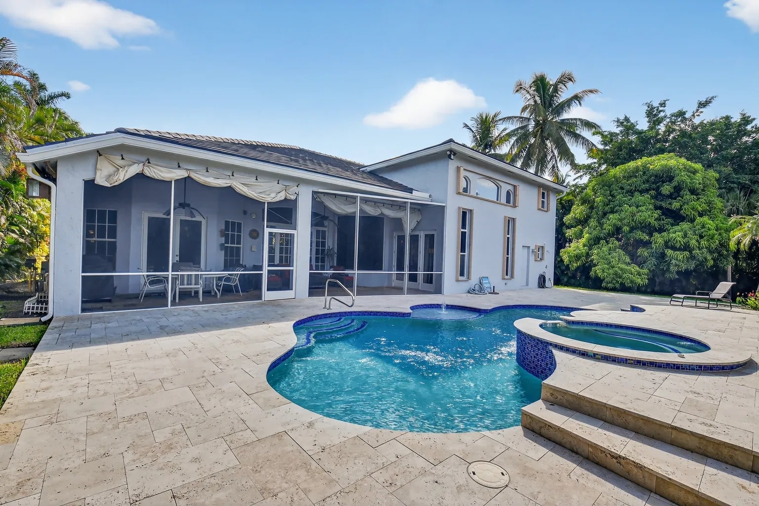 Backyard view of a house with a swimming pool, hot tub, and patio area.
