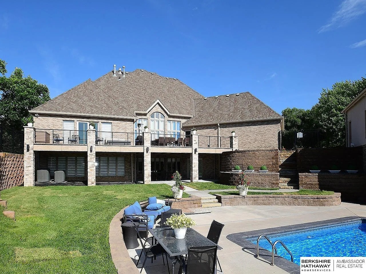 Large brick house with a spacious backyard, patio, and swimming pool.