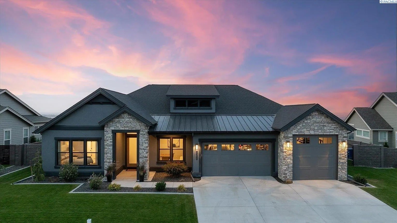 Modern single-story house with stone accents, large windows, and a two-car garage at sunset.