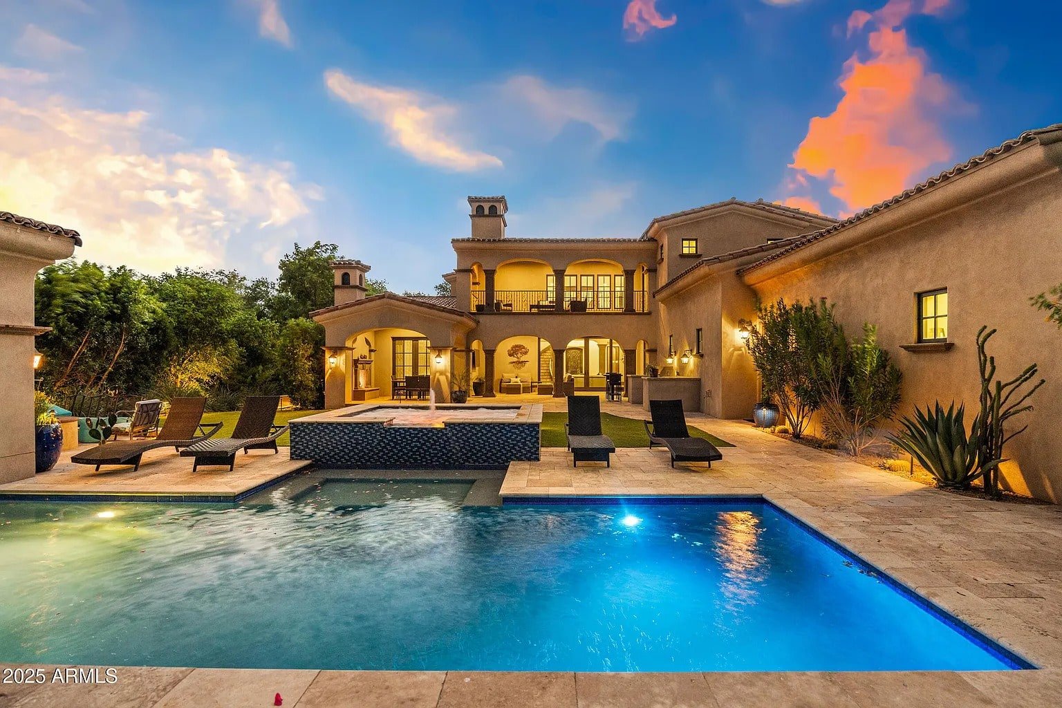 Luxury villa with a pool and hot tub, surrounded by lounge chairs and lush greenery.