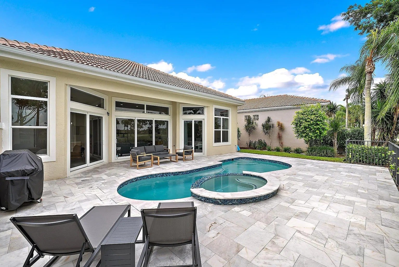 Backyard with a swimming pool, hot tub, patio furniture, and a barbecue grill.