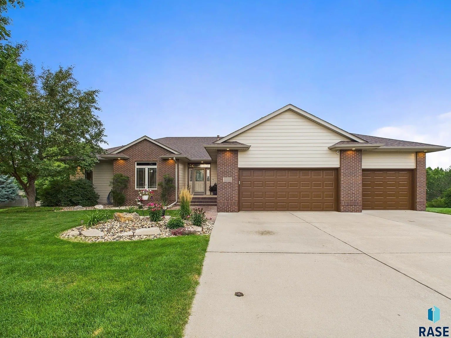 Single-story house with a three-car garage, brick and siding exterior, and landscaped front yard.