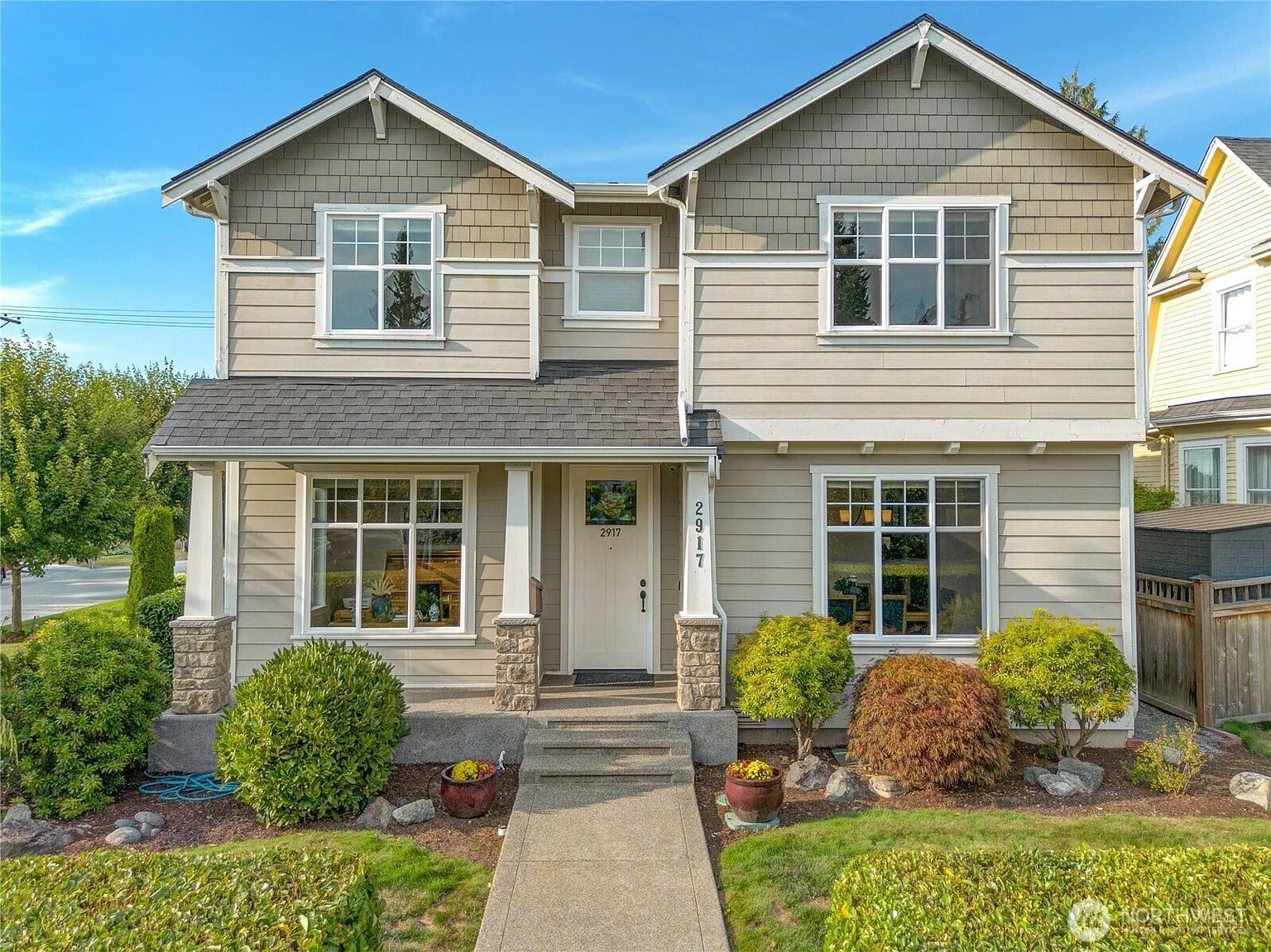 Two-story suburban house with a gray exterior, white trim, and landscaped front yard.