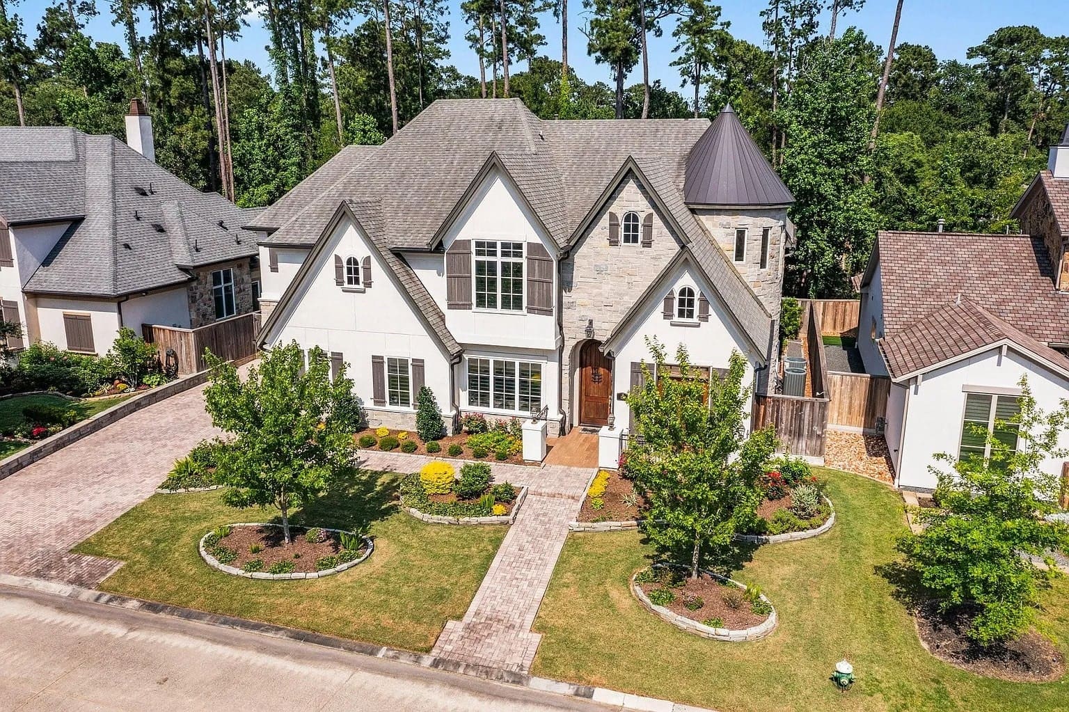 Large two-story house with a gray roof, front yard, and trees, surrounded by similar homes.