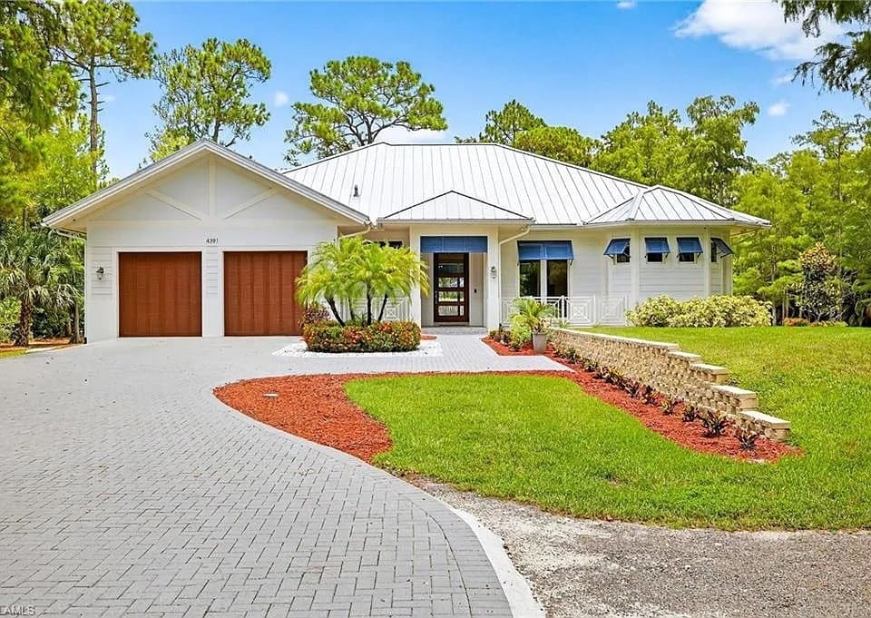 Modern white house with a metal roof, two-car garage, and landscaped front yard.