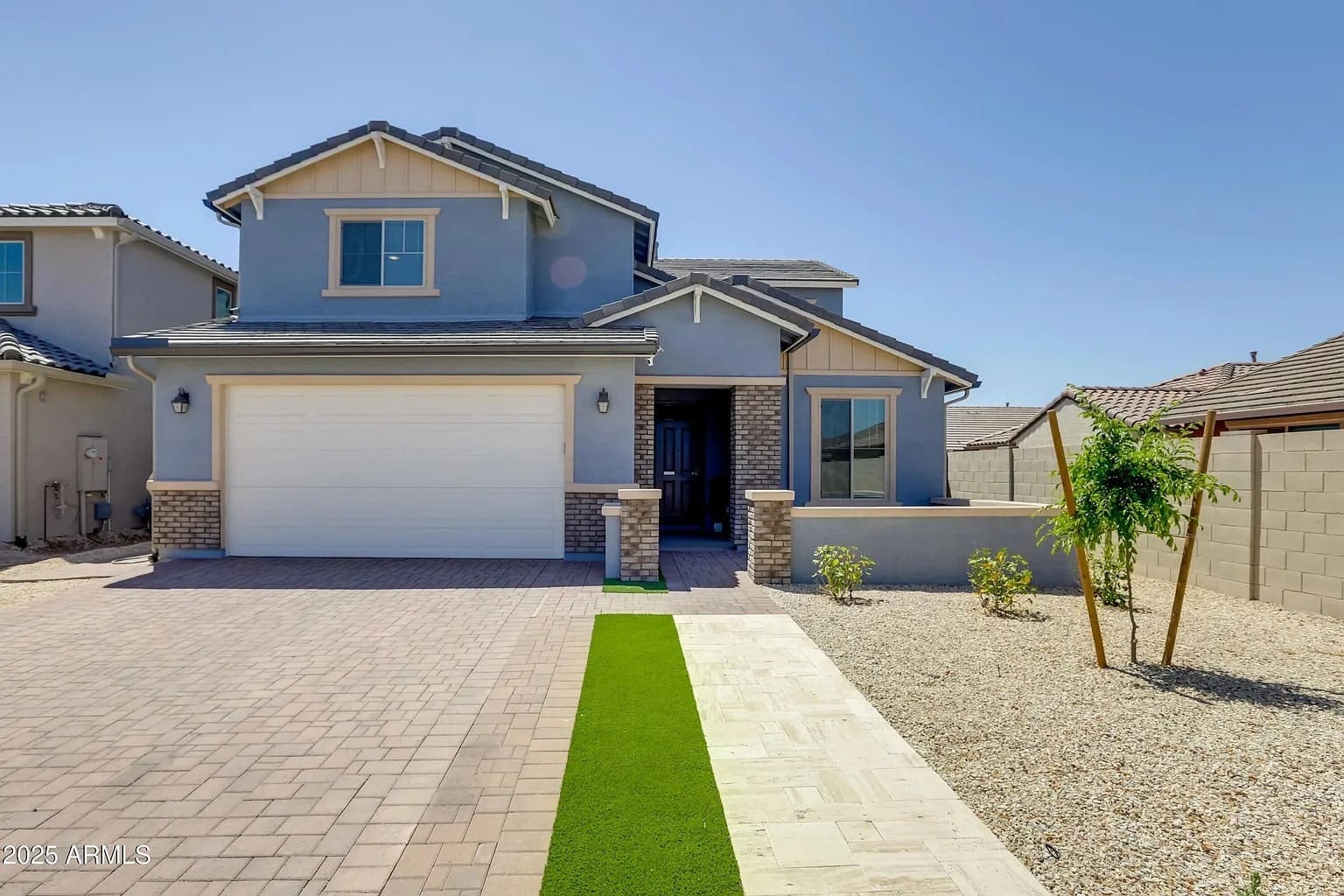 Two-story house with a gray exterior, white garage door, and landscaped front yard.