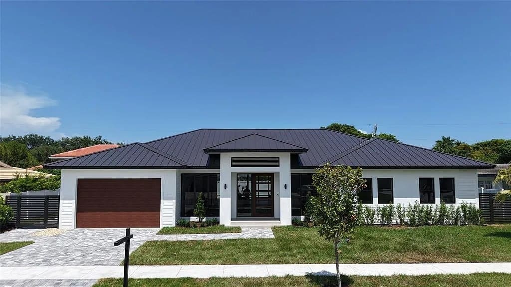 Modern single-story house with a dark roof, white exterior, and a brown garage door.