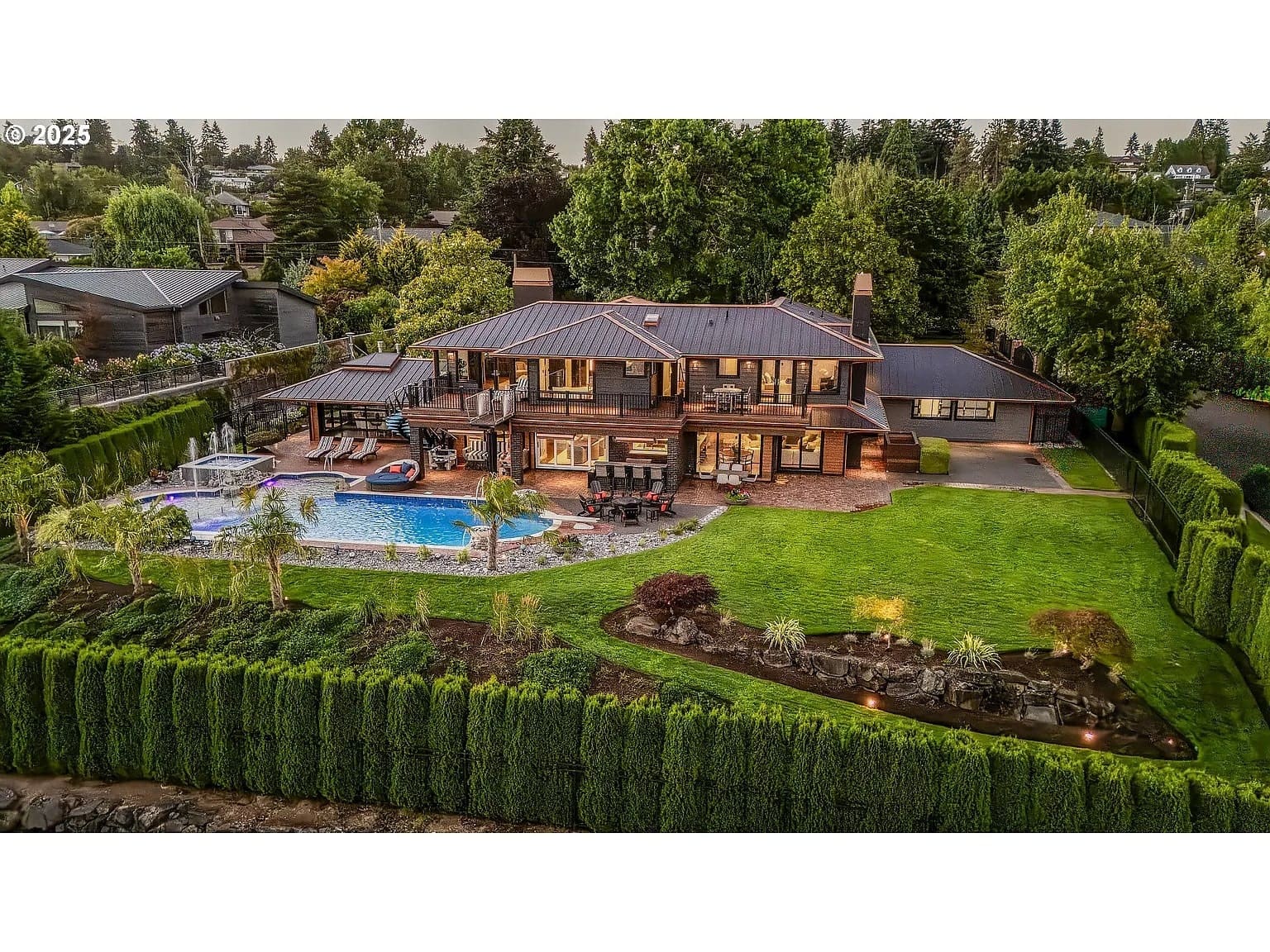 Luxurious two-story house with a pool, surrounded by greenery and landscaped garden.