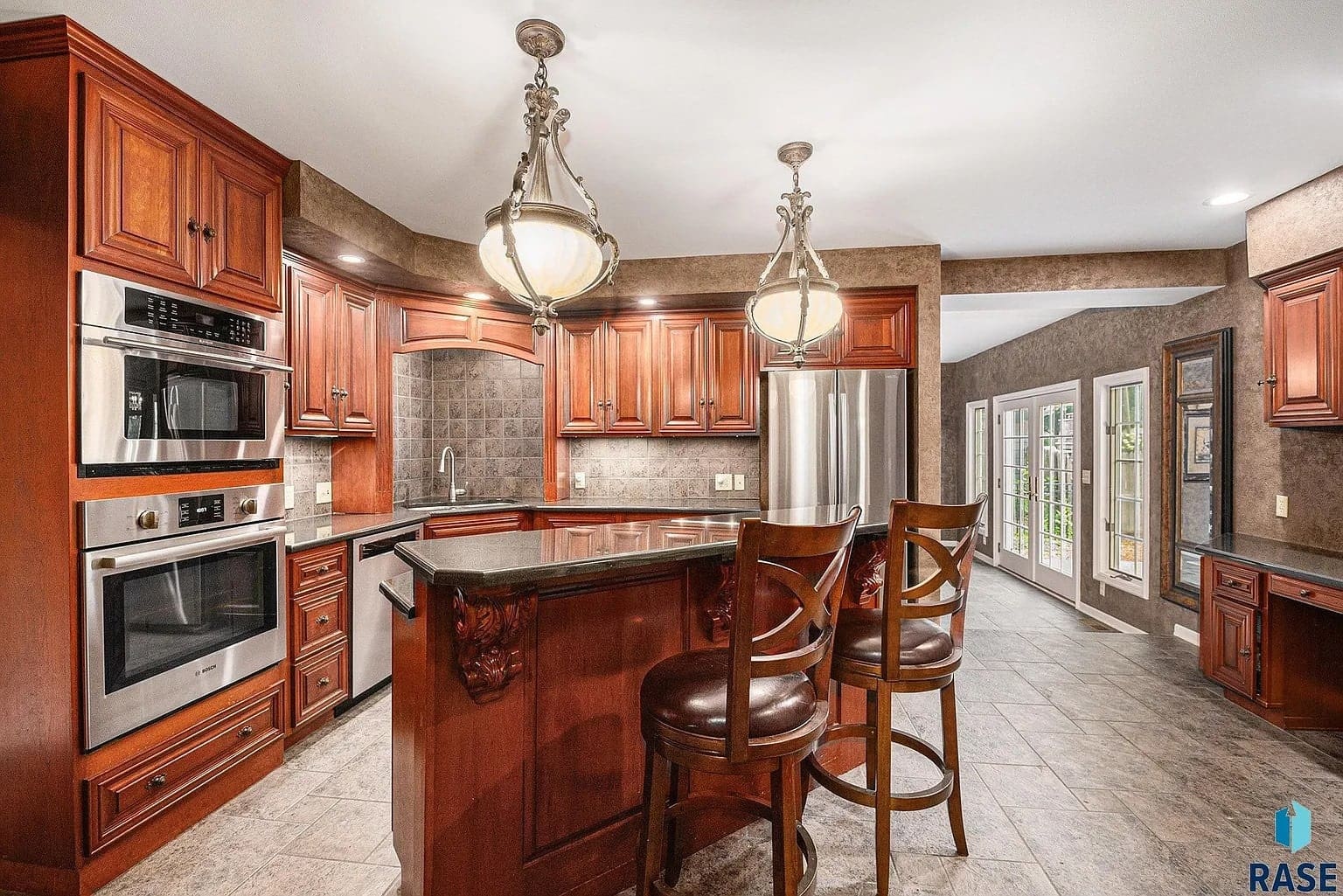 Spacious kitchen with wooden cabinets, stainless steel appliances, and a central island with bar stools.