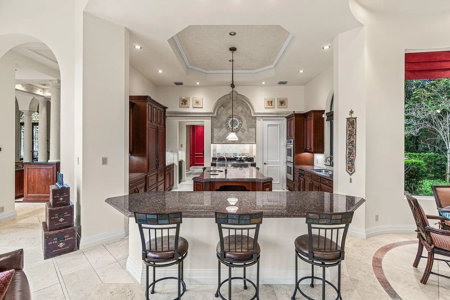 Spacious kitchen with a central island, bar stools, dark wood cabinets, and stainless steel appliances.

