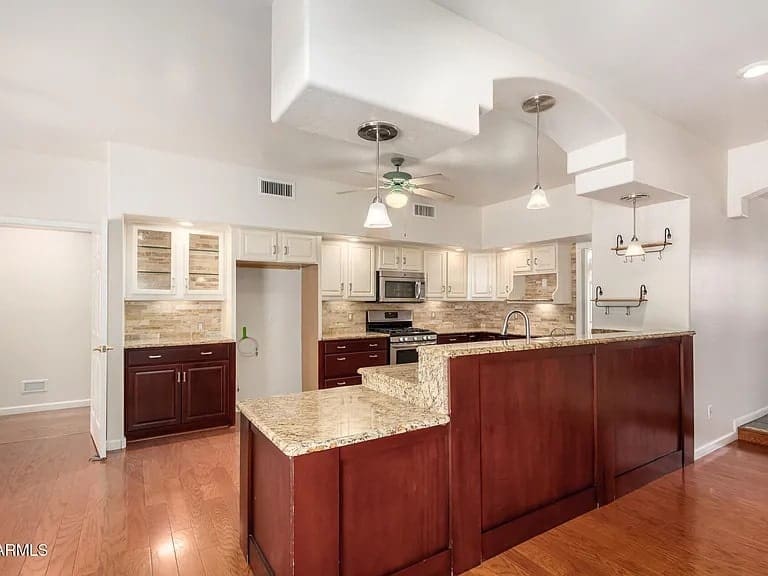 Modern kitchen with wooden cabinets, granite countertops, stainless steel appliances, and recessed lighting.
