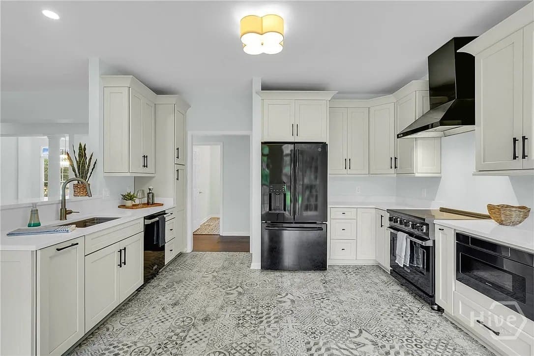 Modern kitchen with patterned tile floor, white cabinets, black appliances, and a central light fixture.
