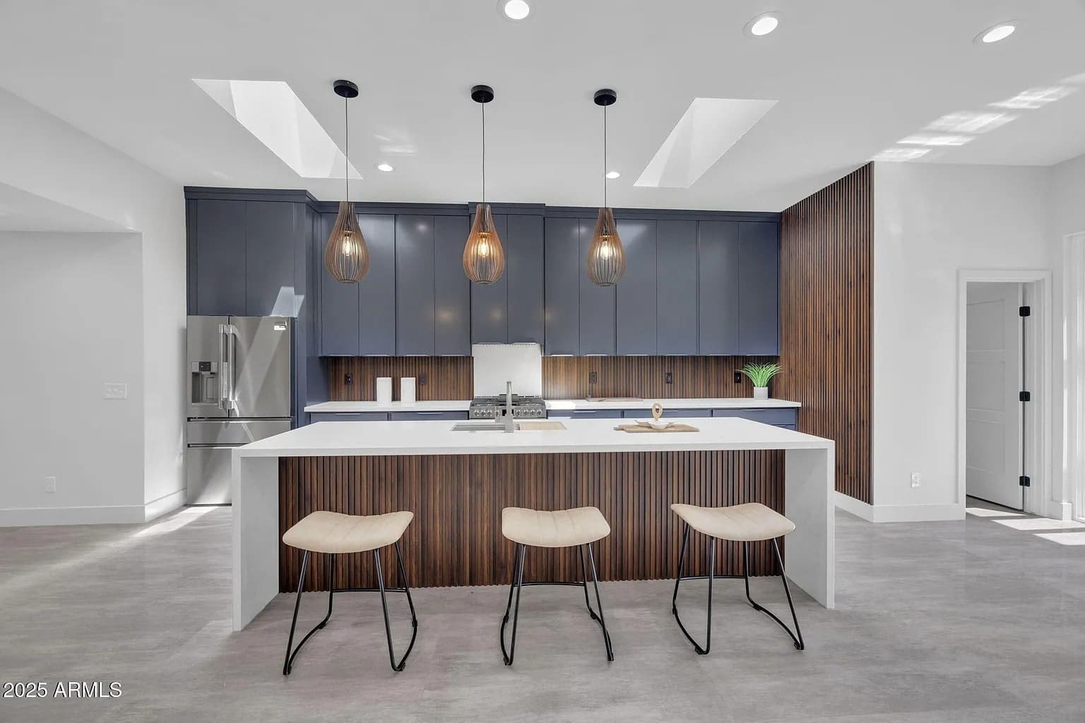 Modern kitchen with a large island, pendant lights, bar stools, and sleek cabinetry.
