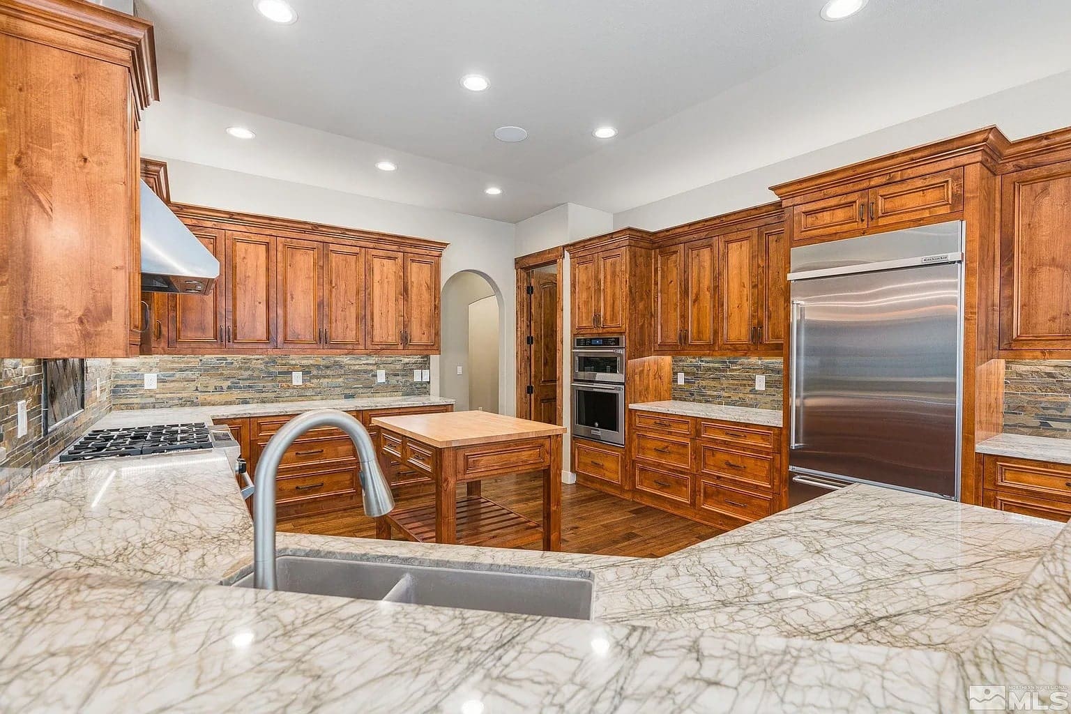 Spacious kitchen with wooden cabinets, marble countertops, stainless steel appliances, and a central island.