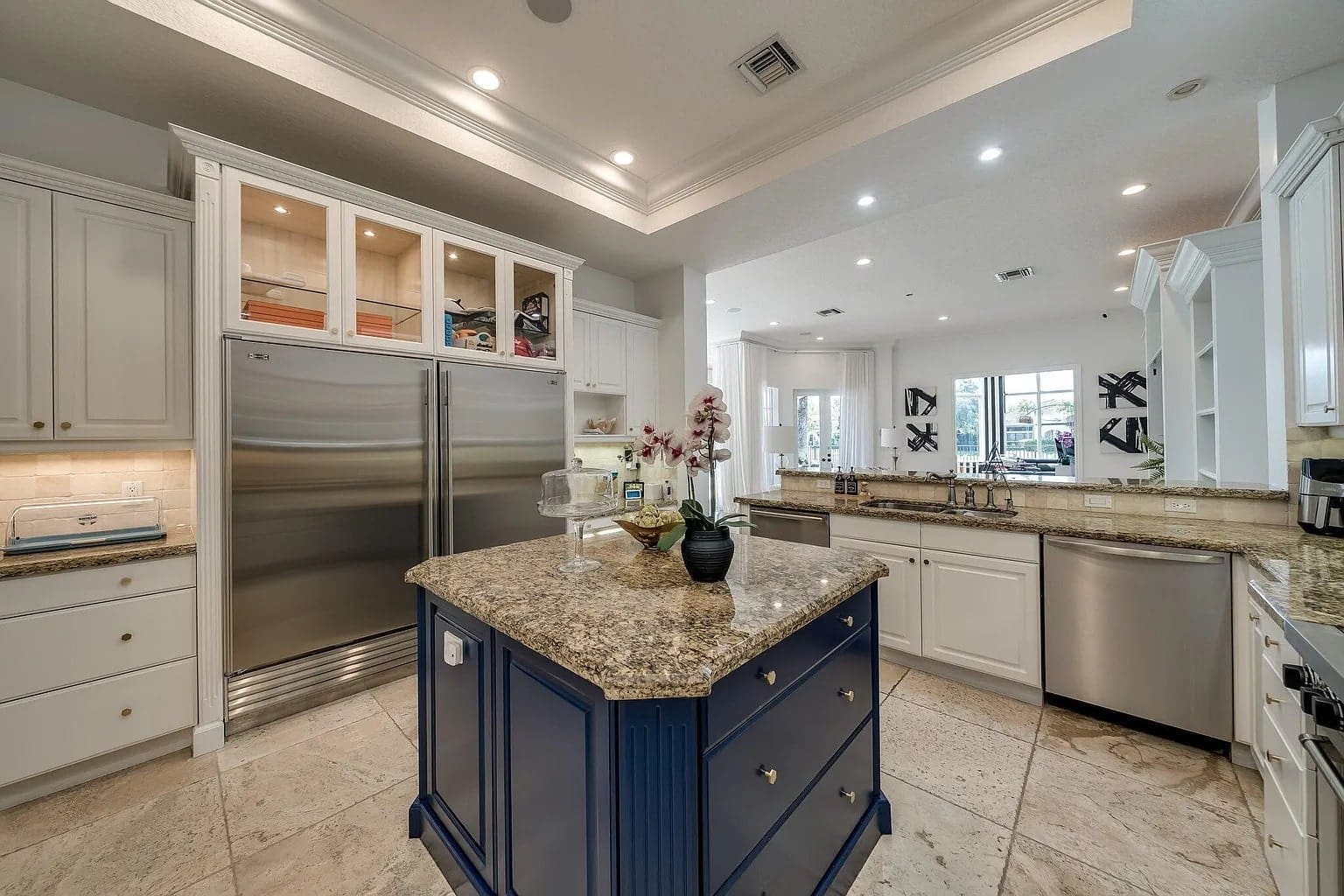 Spacious modern kitchen with granite countertops, blue island, stainless steel appliances, and white cabinetry.
