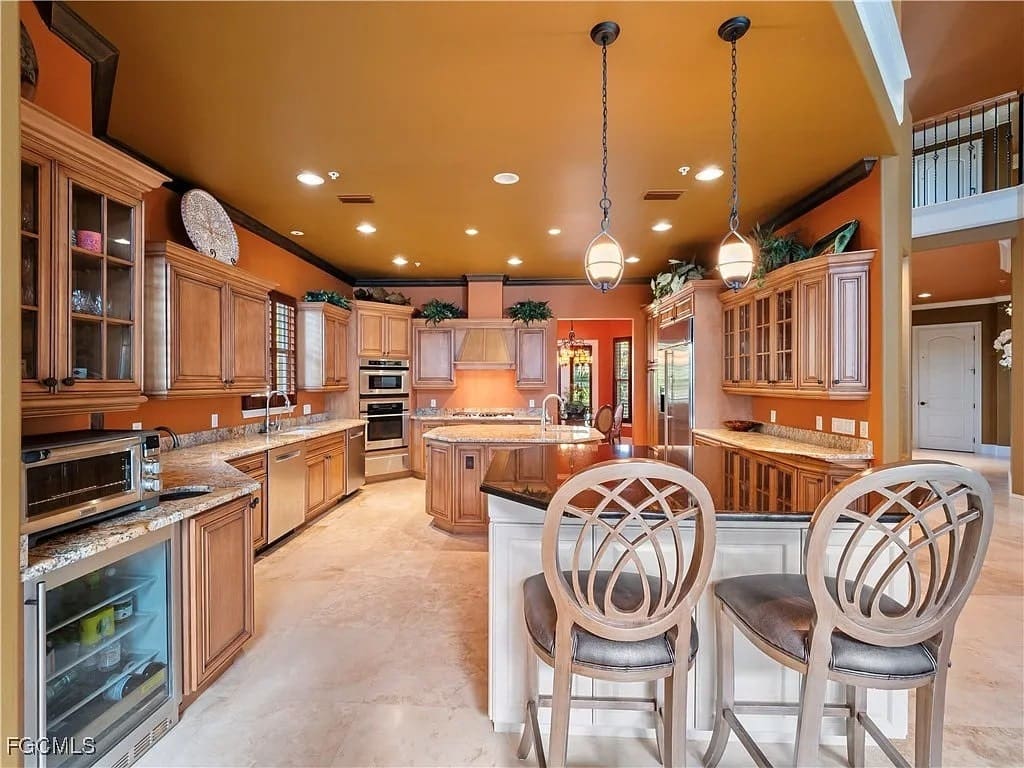 Spacious kitchen with wooden cabinets, marble countertops, island, and pendant lighting.
