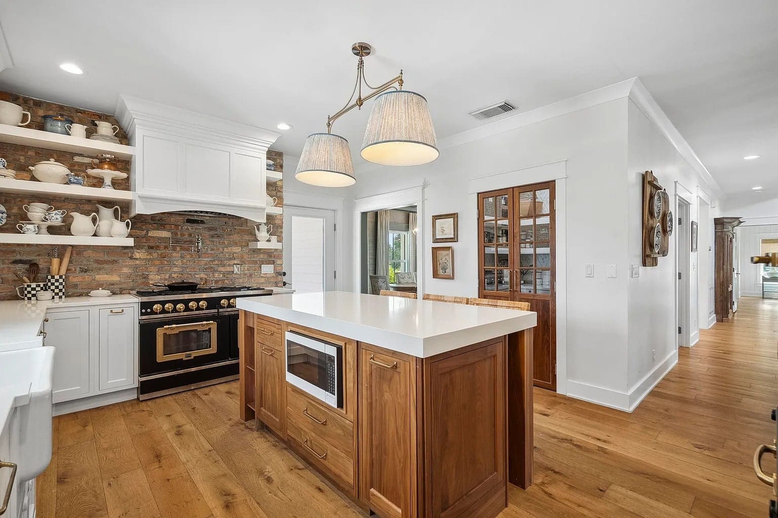 Rustic kitchen with wooden island, brick backsplash, open shelves, and modern appliances.
