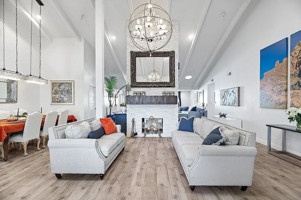 Spacious living room with modern decor, two sofas, a fireplace, and a chandelier.
