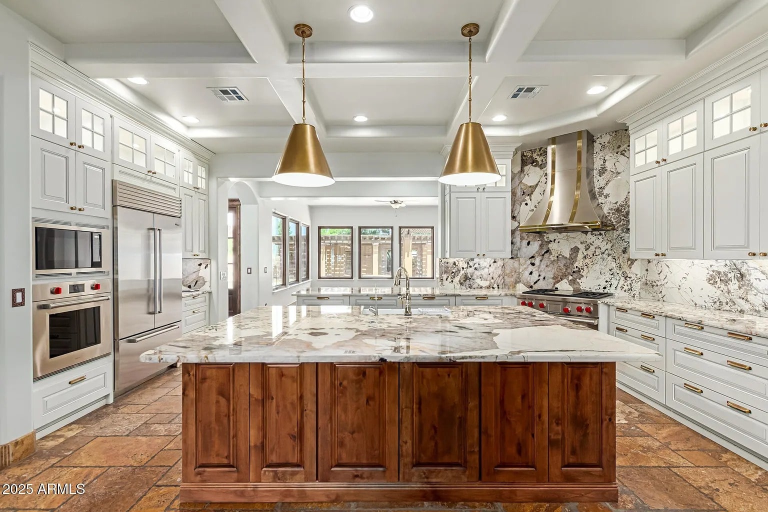 Spacious modern kitchen with marble countertops, wooden island, and stainless steel appliances.