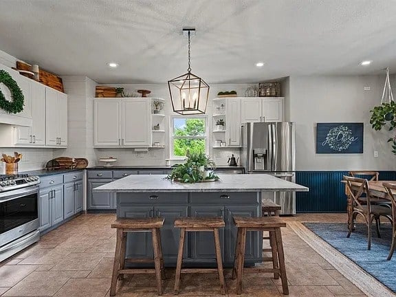 Modern kitchen with a large island, wooden stools, and stainless steel appliances.