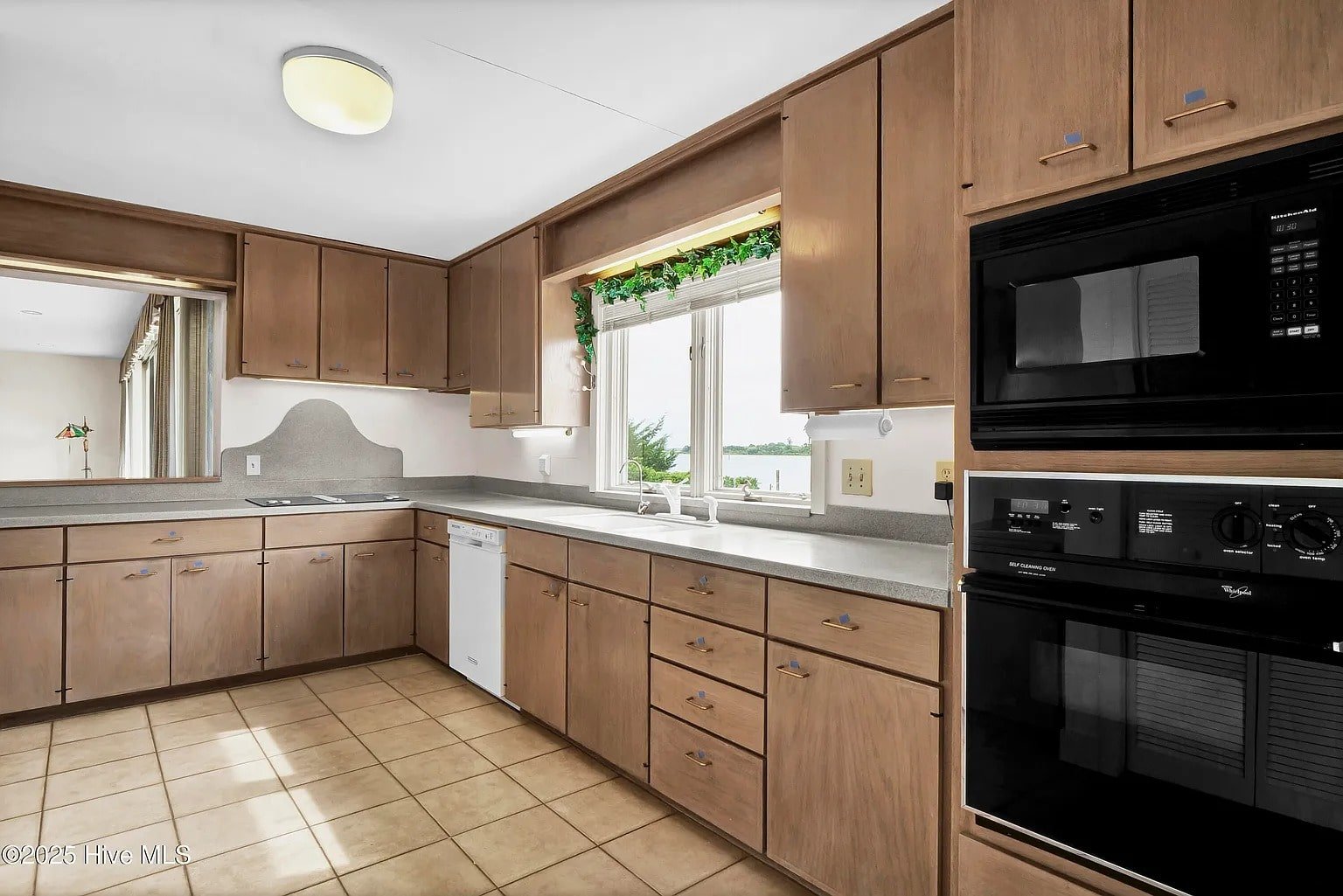 Spacious kitchen with wooden cabinets, black appliances, and a window overlooking a scenic view.