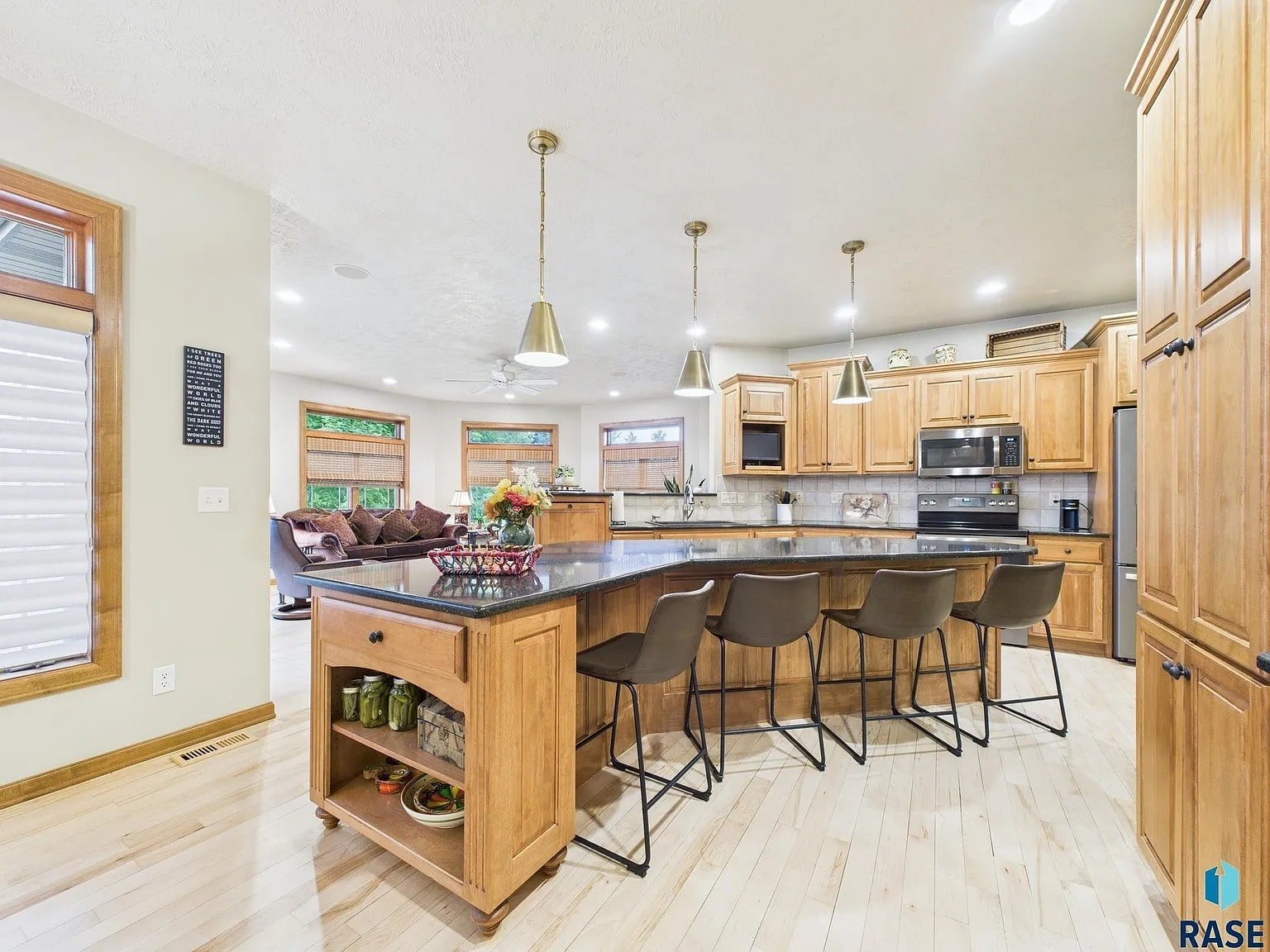Spacious kitchen with wooden cabinets, large island, bar stools, and stainless steel appliances.