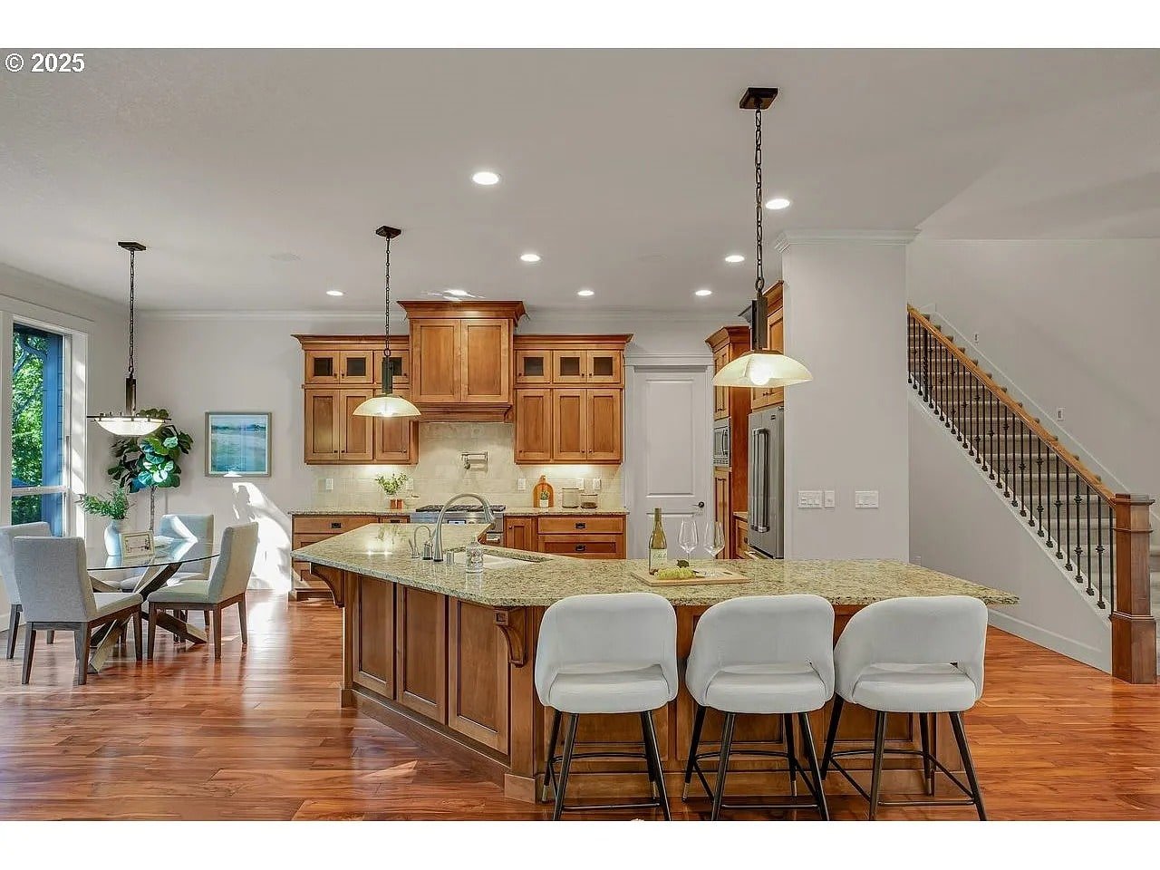 Spacious kitchen with wooden cabinets, large island, and adjacent dining area with natural light.