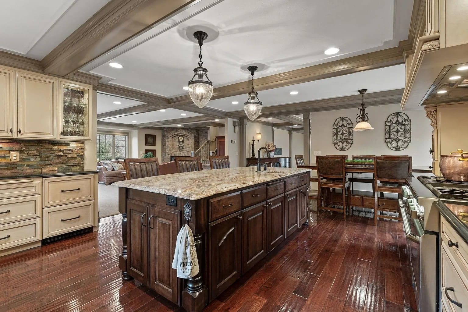 Spacious kitchen with large island, wooden cabinets, pendant lights, and adjacent dining area.