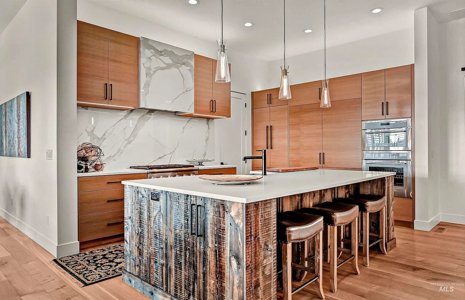 Modern kitchen with wooden cabinets, marble backsplash, island with rustic wood finish, and pendant lights.