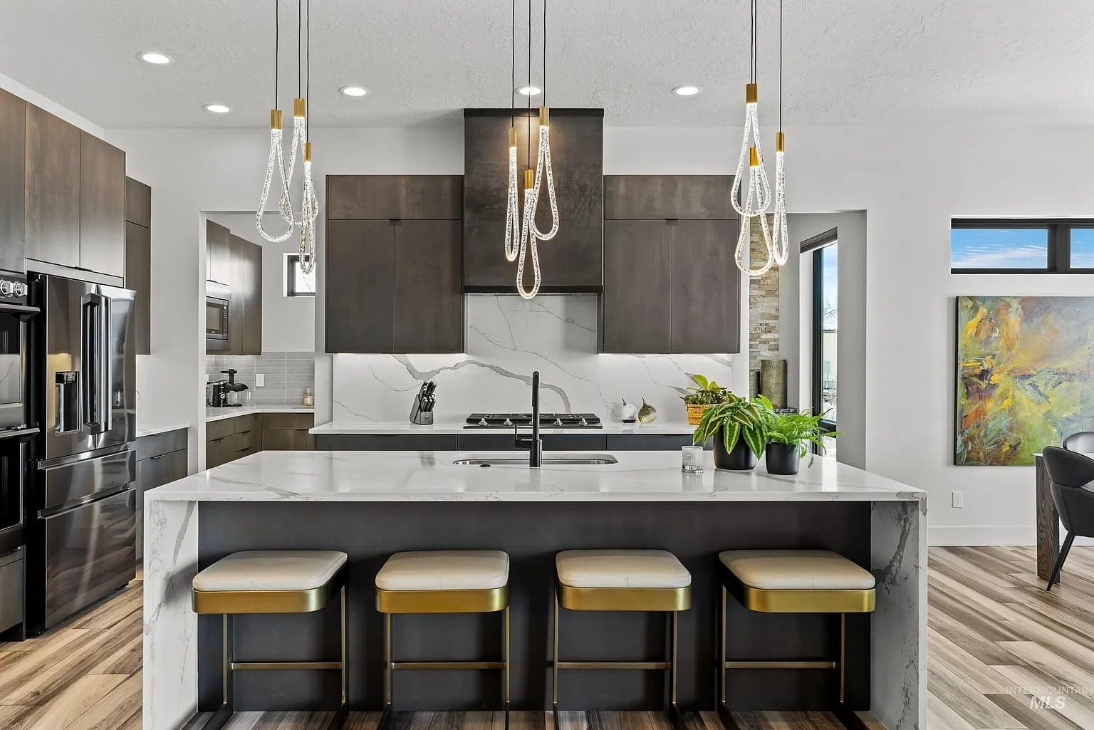 Modern kitchen with dark wood cabinets, marble island, pendant lights, and bar stools.