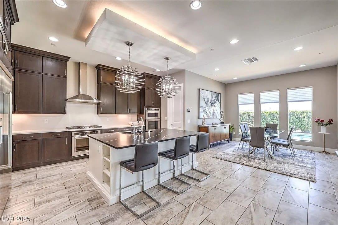 Modern kitchen and dining area with dark wood cabinets, island seating, and large windows.
