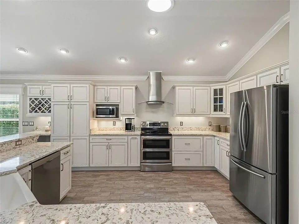 Modern kitchen with white cabinets, stainless steel appliances, granite countertops, and recessed lighting.