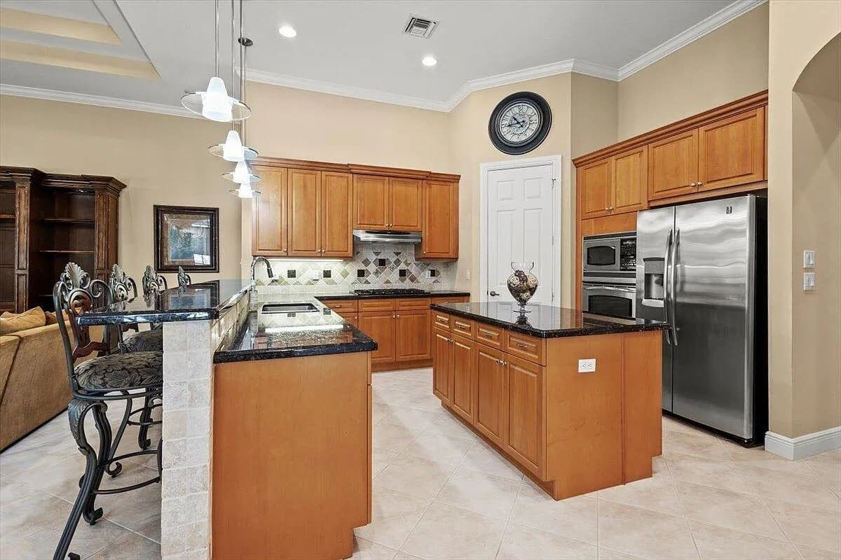 Spacious kitchen with wooden cabinets, black countertops, stainless steel appliances, and a central island.