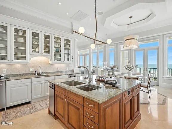 Spacious kitchen with island, modern appliances, and ocean view through large windows.