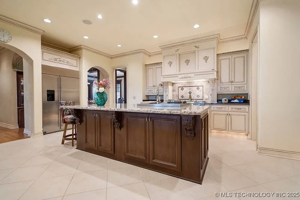 Spacious kitchen with a large island, ornate cabinetry, and stainless steel appliances.