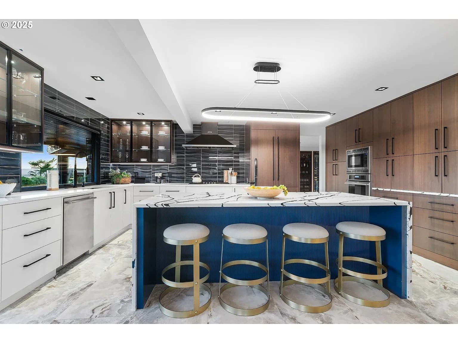 Modern kitchen with a large island, bar stools, and sleek cabinetry in wood and black finishes.