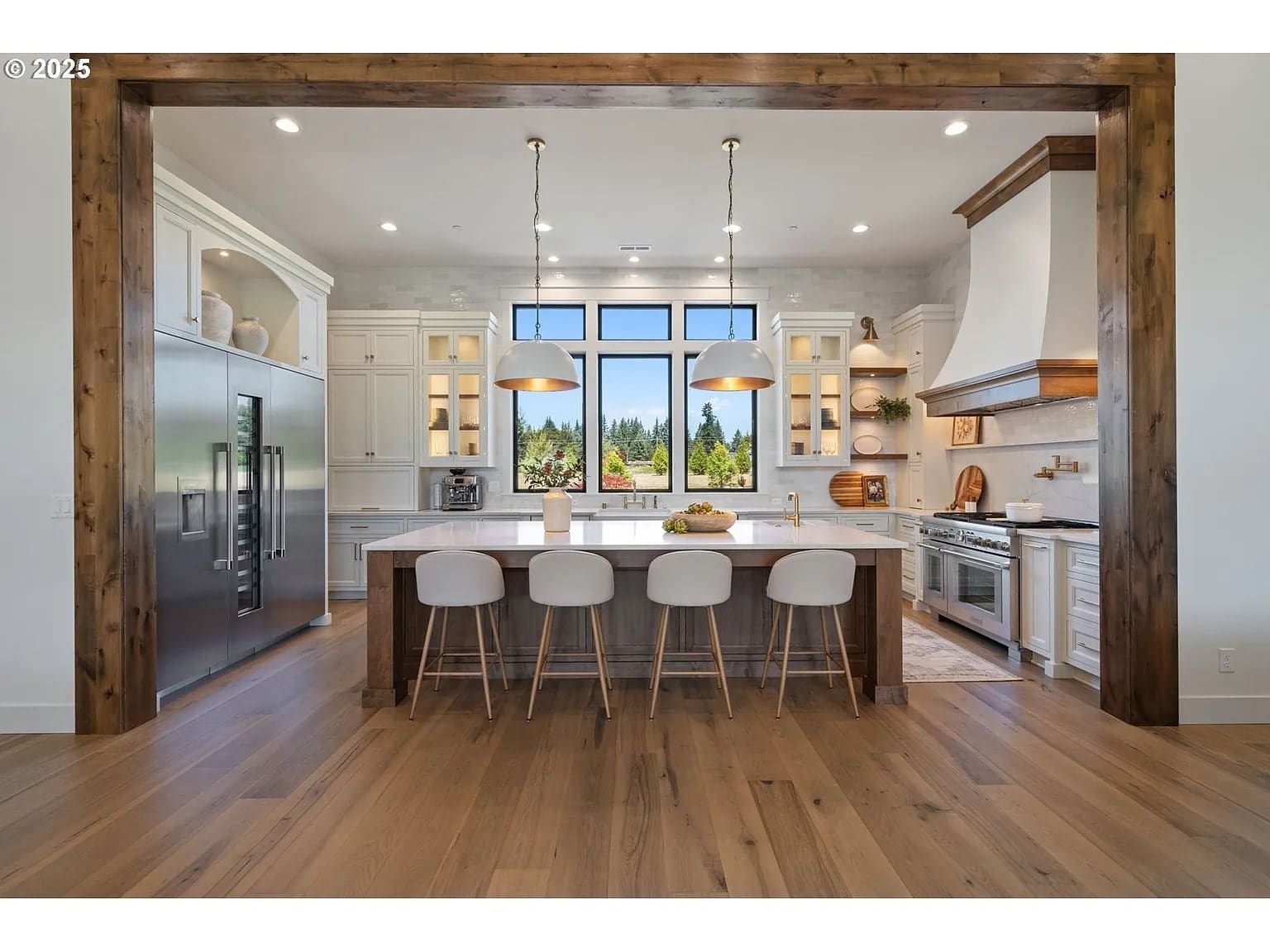 Spacious modern kitchen with large island, wooden accents, and stainless steel appliances.
