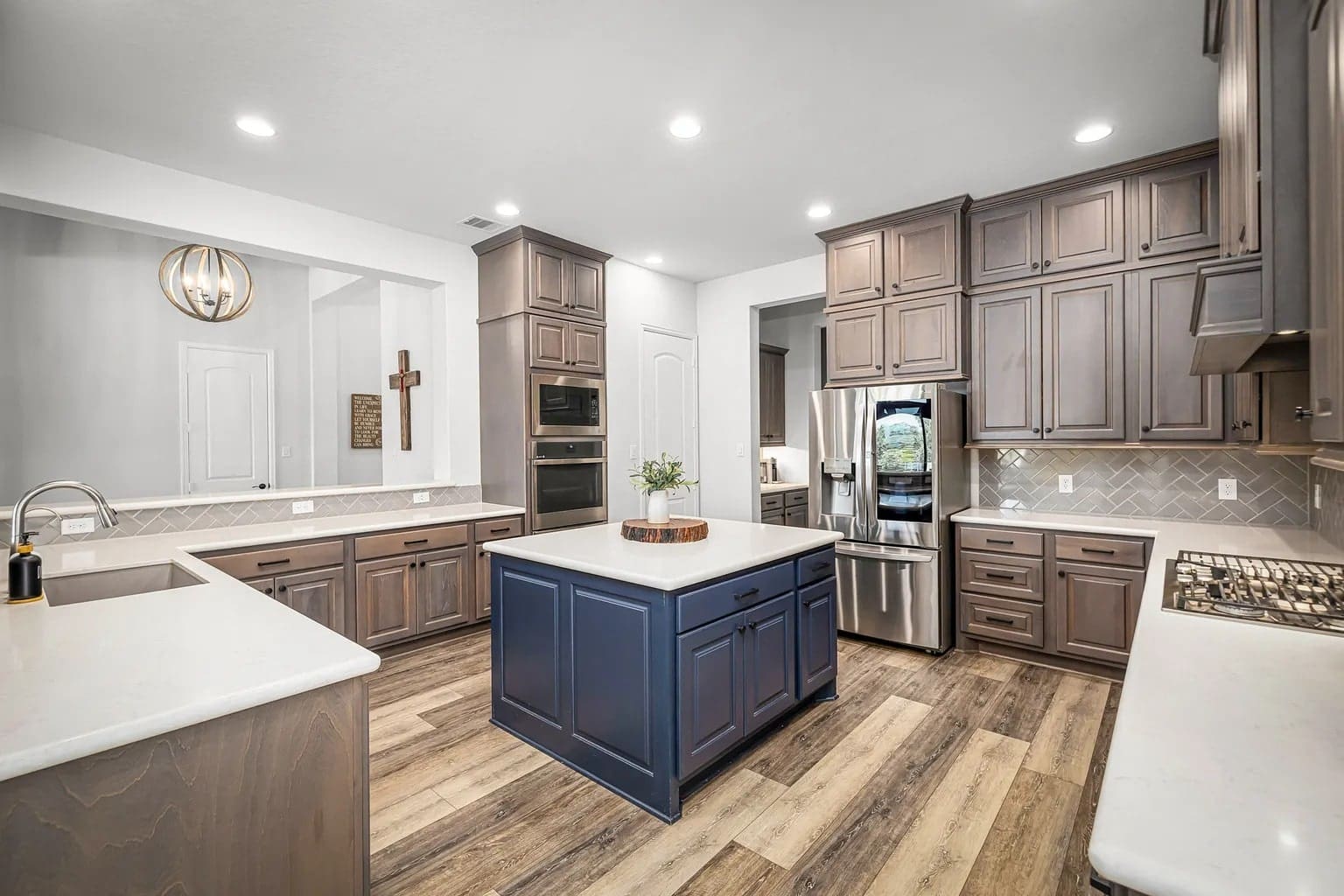 Modern kitchen with wooden cabinets, center island, stainless steel appliances, and herringbone backsplash.
