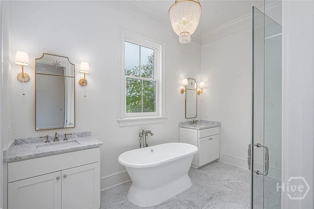 Elegant bathroom with a freestanding bathtub, marble countertops, and a glass shower enclosure.