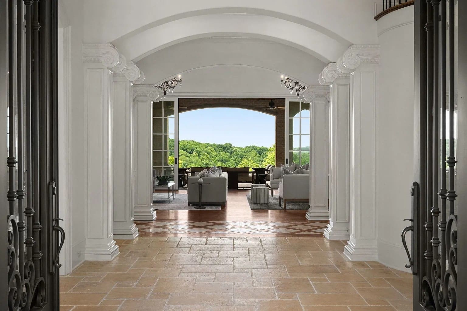 Elegant hallway with arched ceiling leading to a living room and outdoor view of greenery.
