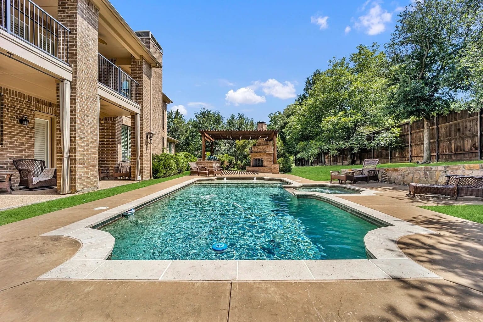 Backyard with a swimming pool, patio furniture, and a wooden pergola under a clear sky.
