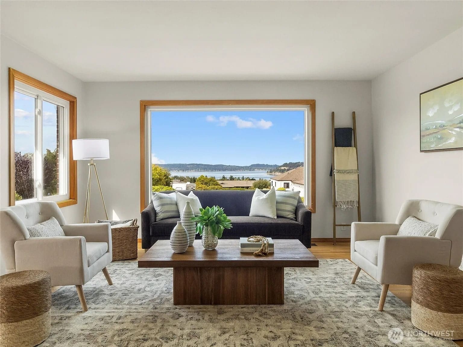 Modern living room with large window view, featuring a sofa, armchairs, and a wooden coffee table.

