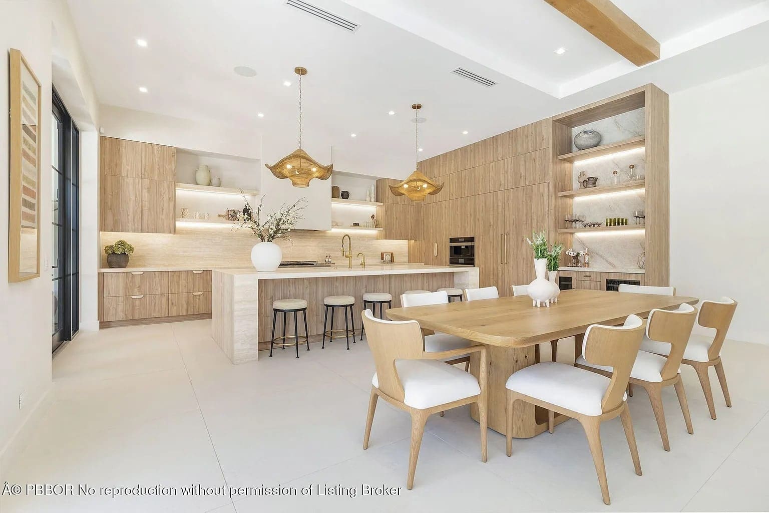 Modern kitchen and dining area with wooden cabinets, large table, and pendant lights.
