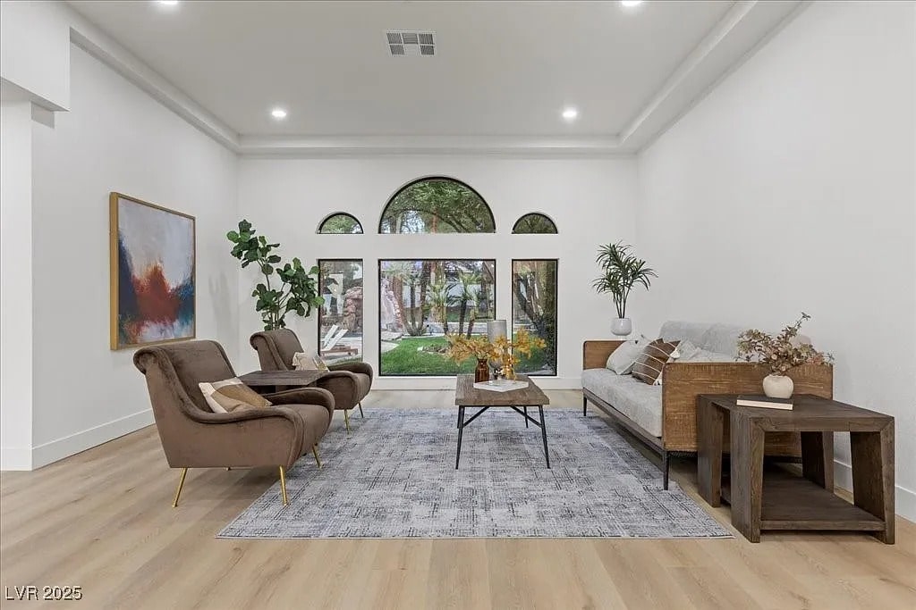 Spacious living room with modern furniture, large windows, and a view of a garden.