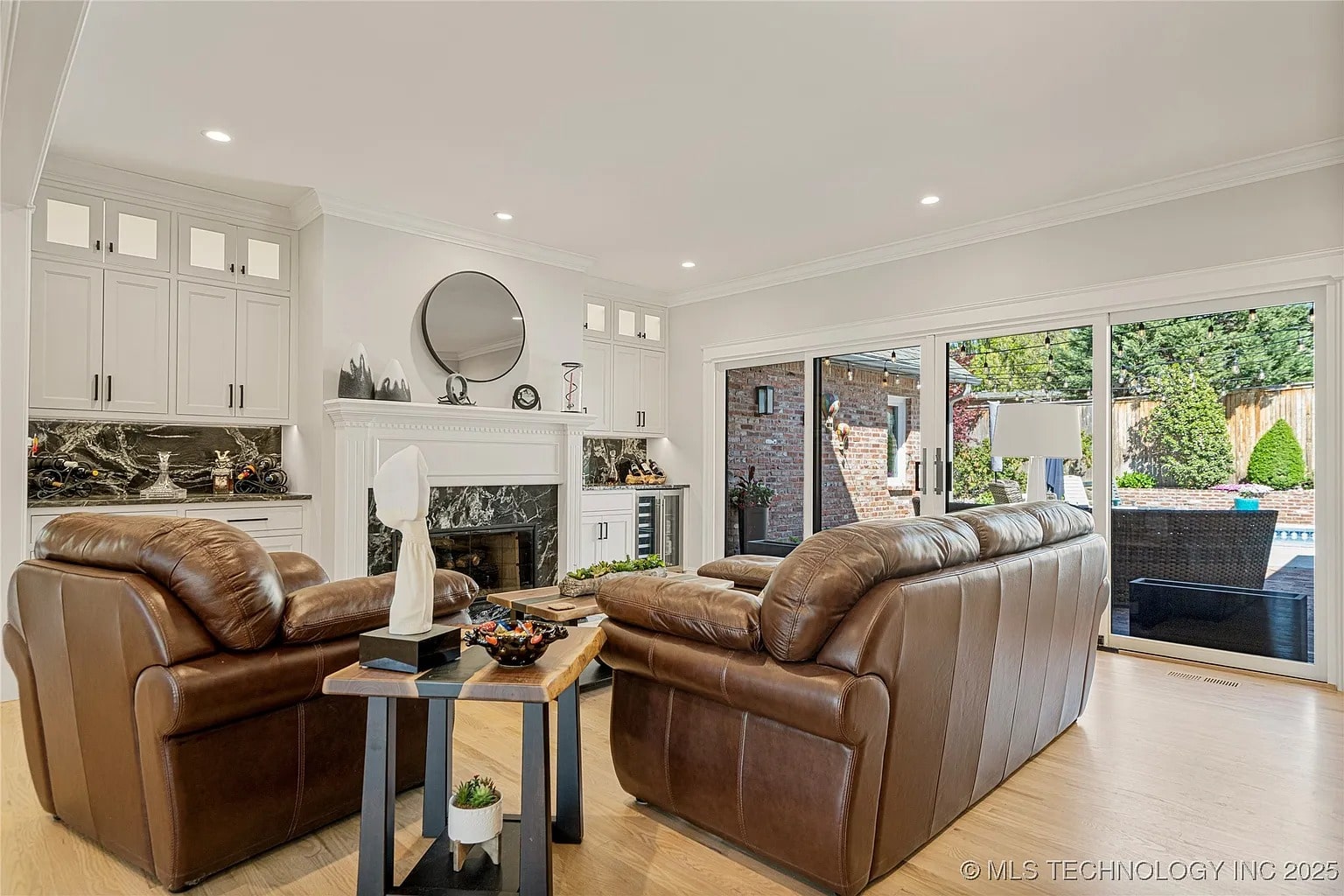 Living room with leather sofas, fireplace, and large sliding glass doors leading to a patio.