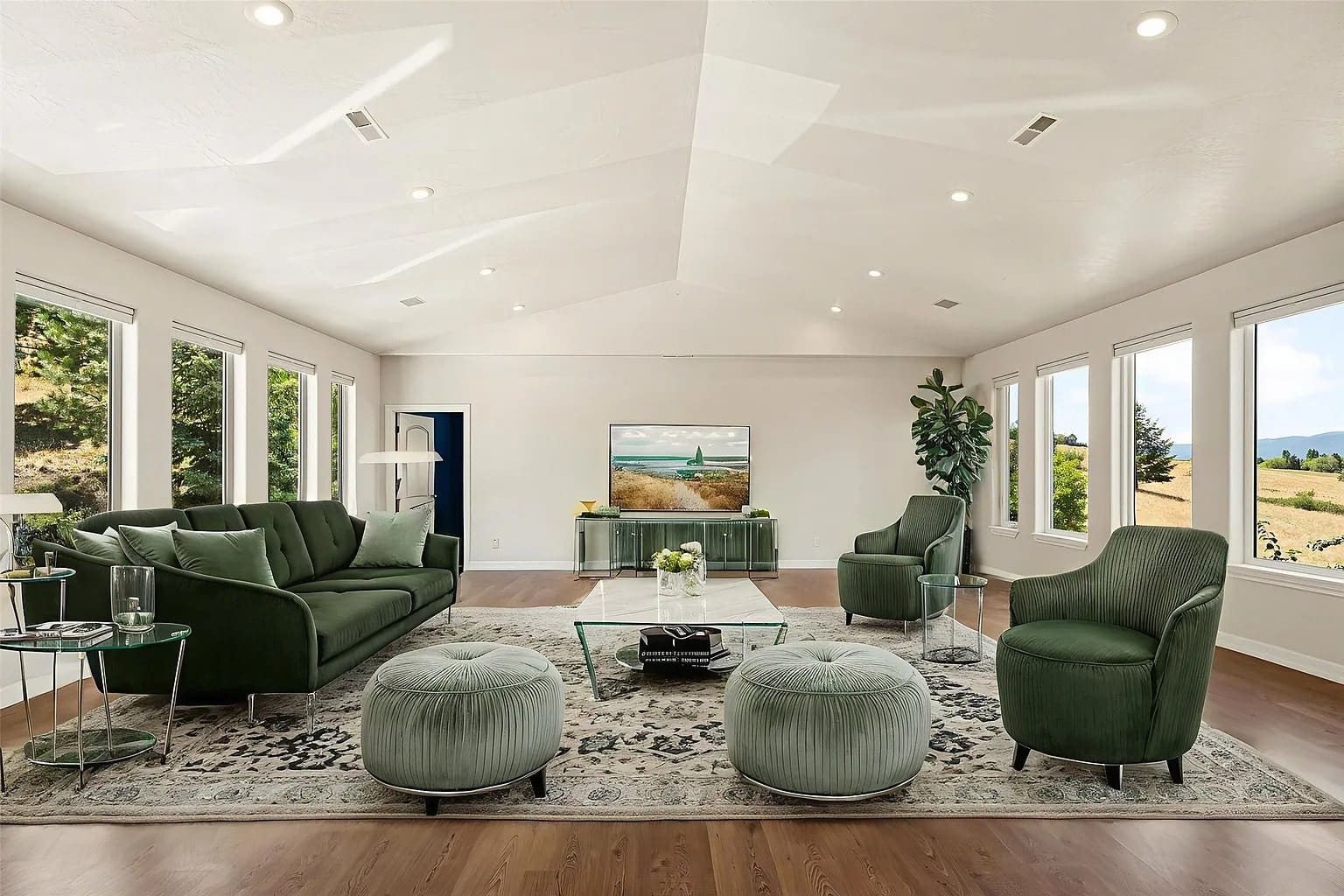 Spacious living room with green furniture, large windows, and a wall-mounted TV.